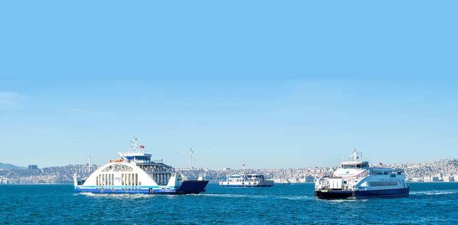 İZDENİZ arabalı vapurları İzmir Körfezi'nde yan yana seyrederken, arka planda kent silueti