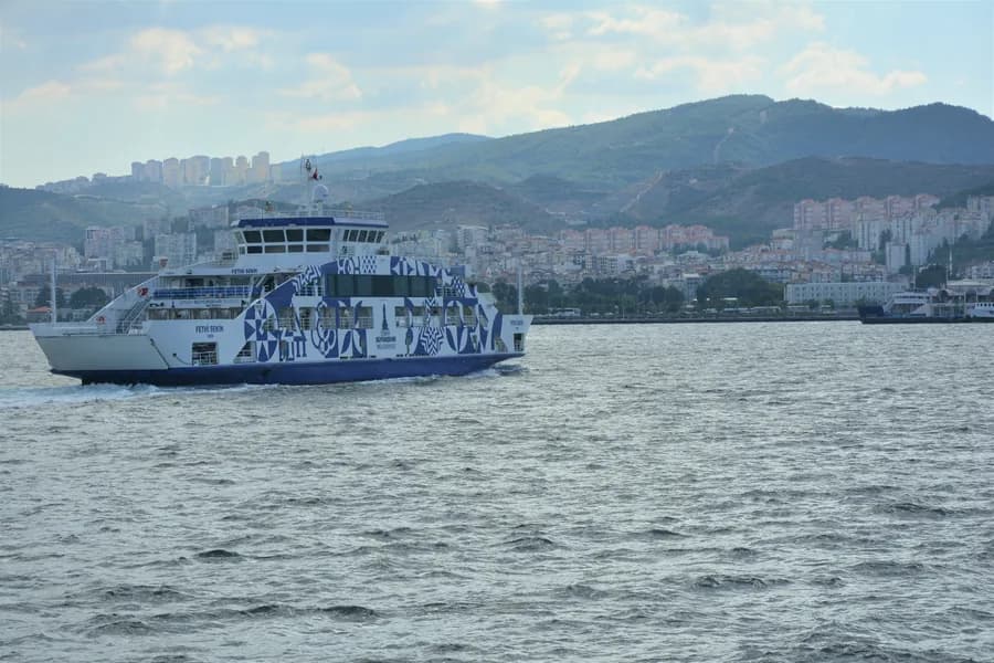 Arabalı vapur Karşıyaka yakasına yaklaşırken, arka planda yamaçtaki yerleşim